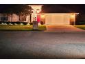 Night view of a brick home featuring a well-lit two-car garage and manicured lawn at 1941 Spruce Creek Lndg, Port Orange, FL 32128
