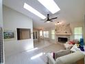 Bright living room featuring skylights, a ceiling fan, and a stone fireplace, creating a cozy and inviting atmosphere at 1941 Spruce Creek Lndg, Port Orange, FL 32128