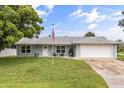 Charming single-story home features a well-manicured lawn, American flag, and inviting front porch seating area at 2529 Umbrella Tree Dr, Edgewater, FL 32141