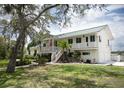 Inviting two-story home featuring a charming front porch, well-manicured lawn, and lush landscaping at 2950 Sunset Dr, New Smyrna Beach, FL 32168