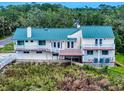 Stunning elevated exterior featuring a green roof, multiple balconies, and lush landscaping for privacy at 2950 Sunset Dr, New Smyrna Beach, FL 32168
