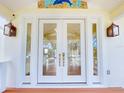 Elegant front door with glass panes and sidelights, adorned with a mosaic and stylish lanterns at 2950 Sunset Dr, New Smyrna Beach, FL 32168