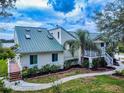 View of the back of the home with a metal roof, private deck, landscaping, and walkway at 2950 Sunset Dr, New Smyrna Beach, FL 32168