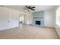 Bright living room features tile floors, a ceiling fan, and a painted brick fireplace at 3044 Pine Tree Dr, Edgewater, FL 32141