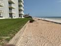 A pristine beach with soft sand next to a grassy lawn area that leads up to a condominium complex at 5201 S Atlantic Ave # 407A, New Smyrna Beach, FL 32169