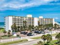 A low aerial view of a beachside condo complex with ample parking, a rec area, and easy beach access at 5201 S Atlantic Ave # 407A, New Smyrna Beach, FL 32169