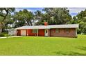 Charming home with brick accents, a well-manicured lawn, and an attached garage at 585 Corbin Park Rd, New Smyrna Beach, FL 32168