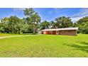 Charming single-story home with a brick facade, garage, and lush lawn and mature trees at 585 Corbin Park Rd, New Smyrna Beach, FL 32168