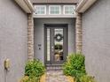 Inviting front door with decorative wreath, flanked by stone columns and lush ferns at 6307 Hanfield Dr, Port Orange, FL 32128