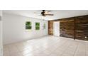 Inviting living room features a wood accent wall, tile flooring, and natural light from the two windows at 680 Buford Ave, Orange City, FL 32763