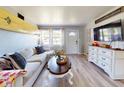 Inviting living room featuring a surfboard accent, comfortable couch, light wood floors, and a view through bright windows at 903 Conrad Dr, New Smyrna Beach, FL 32168