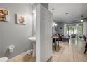 Stylish powder room featuring a pedestal sink adjacent to an open-concept living area at 1453 River Rock Ct, Oviedo, FL 32765
