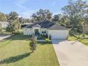 Single-story home boasting an attached garage, mature trees, and lush green lawn at 1929 Pioneer Trl, New Smyrna Beach, FL 32168