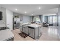 Open-concept kitchen with stainless steel appliances and an island overlooking the dining area and living room at 2731 Neverland Dr, New Smyrna Beach, FL 32168