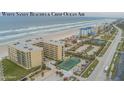 Aerial view of beachfront condos with a tennis court, palm trees, and ample parking near the ocean at 4575 S Atlantic Ave # 6607, Ponce Inlet, FL 32127