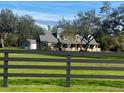Beautiful exterior view of a charming country home with a black wooden fence, green grass and blue skies at 5832 Michelle Ln, Sanford, FL 32771