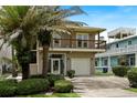Two-story home with a balcony, garage, and a front yard with palm trees, complementing the coastal neighborhood at 6956 Turtlemound Rd, New Smyrna Beach, FL 32169