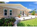 Charming stone home features a patio with seating, complemented by lush greenery and a well-manicured lawn at 22 Sand Dune Dr, New Smyrna Beach, FL 32169