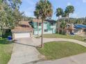 Two-story home with garage, circular driveway, and mature palms, adding charm to the property's overall appeal at 2715 Pine Tree Dr, Edgewater, FL 32141