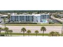 Expansive aerial view of the condo building featuring a pool, parking, beach access and surrounding residential neighborhood at 3700 S Atlantic Ave # 108, New Smyrna Beach, FL 32169