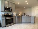 Modern kitchen featuring gray cabinets, stainless steel appliances, and a view into the adjacent living spaces at 3919 Willowbrook Dr, Edgewater, FL 32141