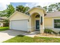 Home exterior featuring an attached garage, covered entryway, and well-kept lawn at 4623 Secret River Trl, Port Orange, FL 32129