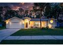 Inviting home exterior with a lush lawn, mature trees, and a warm, welcoming glow at dusk at 4623 Secret River Trl, Port Orange, FL 32129