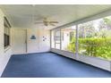 Enclosed porch featuring blue carpet, ceiling fan, and large windows offering plenty of natural light at 5060 Audubon Ave, De Leon Springs, FL 32130