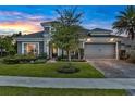 Inviting home featuring stone accents, a well-manicured lawn, and a spacious garage at 6294 W Fallsgrove Ln, Port Orange, FL 32128