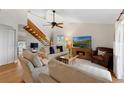 Bright living room featuring a vaulted ceiling, a wooden staircase, and comfortable seating with a TV at 895 Catfish Ave, New Smyrna Beach, FL 32169