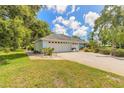 A house with a long driveway, a two-car garage and mature landscaping is neatly manicured at 904 Clubhouse Blvd, New Smyrna Beach, FL 32168
