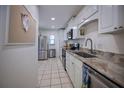 Galley kitchen featuring white cabinets, stainless appliances, granite counters, and tile flooring at 101 N Riverside Dr # 1090, New Smyrna Beach, FL 32168