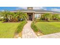 Inviting single-story home featuring a beautifully landscaped front yard with palm trees and a paver walkway at 2939 Bella Flore Ter, New Smyrna Beach, FL 32168