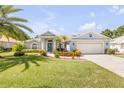 Beautiful single-story home featuring a two-car garage, a well-manicured lawn, and tropical landscaping at 406 Phillips Creek Ln, New Smyrna Beach, FL 32168