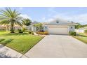 Inviting home exterior with a lush lawn, mature palm trees, and a driveway leading to a two-car garage at 406 Phillips Creek Ln, New Smyrna Beach, FL 32168