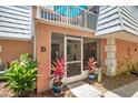 Close-up of the front entrance with potted plants, screened-in porch, and balcony above at 4150 S Atlantic Ave # 111B, New Smyrna Beach, FL 32169