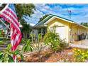 Beautiful home exterior featuring a yellow facade, well-manicured garden, and a quaint American flag at 5146 Pineland Ave, Port Orange, FL 32127