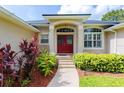 Close-up of the home's inviting red double-door entrance with lush landscaping and abundant sunlight at 6065 Spruce Point Cir, Port Orange, FL 32128