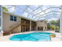 Backyard pool area with a screened enclosure, wooden deck and stairs, and a view of the two-story home at 6065 Spruce Point Cir, Port Orange, FL 32128