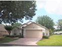 Charming single-story home with a well-maintained lawn, mature trees, and a brick driveway leading to a two-car garage at 3918 Doune Way, Clermont, FL 34711