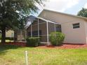 Home's rear exterior features a screened-in porch area and manicured landscaping with decorative mulch at 3918 Doune Way, Clermont, FL 34711