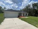 Inviting single-story home featuring a long driveway, attached garage, and well-manicured front lawn at 75 Guava Place Dr, Ocklawaha, FL 32179