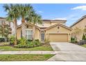 Two-story house with tan exterior, palm trees, and a two-car garage at 6078 Broad Oak Dr, Davenport, FL 33837