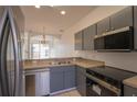 Modern kitchen featuring stainless steel appliances, granite counters, and sleek gray cabinetry at 4712 Hemingway House St, Kissimmee, FL 34746