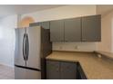 Well-lit kitchen showcasing a stainless steel refrigerator, gray cabinets, and neutral countertops at 4712 Hemingway House St, Kissimmee, FL 34746