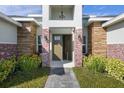 Inviting entryway with brick pillars and lush landscaping at 208 Snowy Orchid Way, Lake Alfred, FL 33850