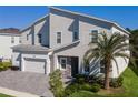 Charming two-story home boasts an attached garage, stone accents, a palm tree, and a manicured lawn at 1758 Oak Blossom Dr, Davenport, FL 33837