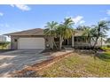 Exterior of home with large lawn, palm trees, and ample parking leading to attached garage at 128 W Juliana Way, Auburndale, FL 33823