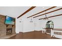 Bright, airy living room featuring vaulted ceilings, wood beams, stone fireplace, and staircase at 128 W Juliana Way, Auburndale, FL 33823