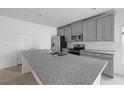 Open concept kitchen with gray cabinets, stainless steel appliances, granite countertops and tiled flooring at 4054 Serene Water Ave, Eustis, FL 32736